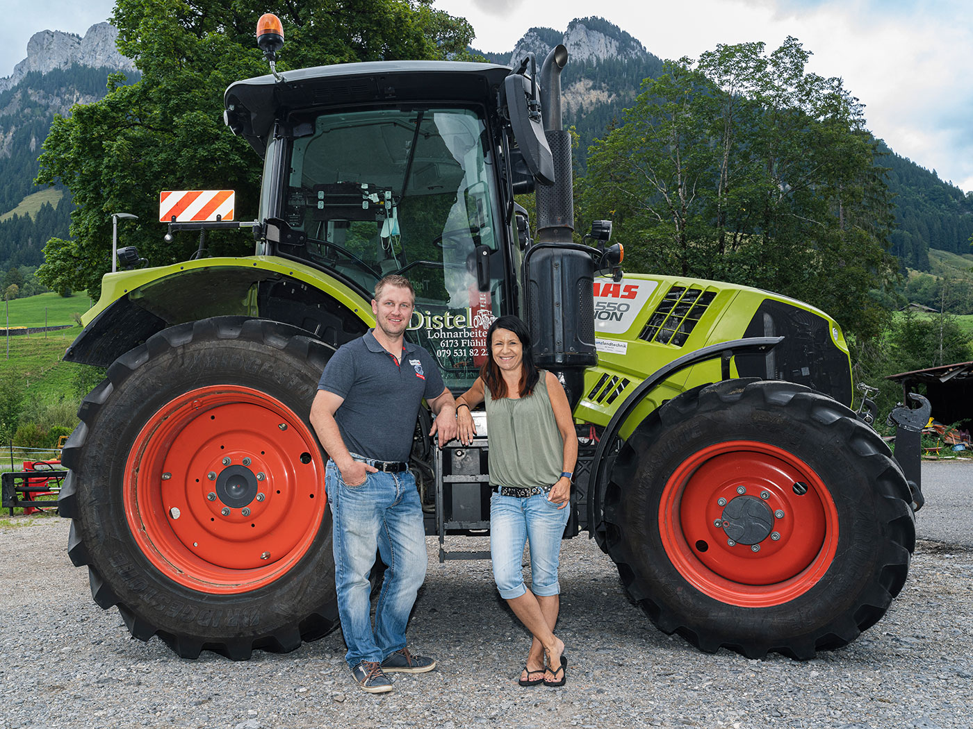 Distel Lohnarbeiten – Sämi und Janine Distel-Ruf vor dem Claas Traktor in Flühli